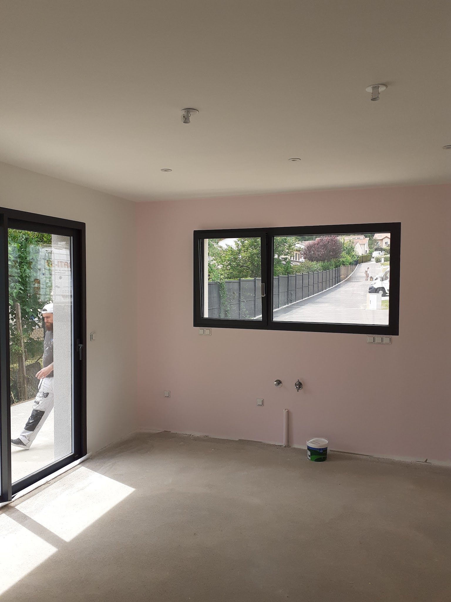 Pièce aux murs rose poudré, pot de peinture au sol