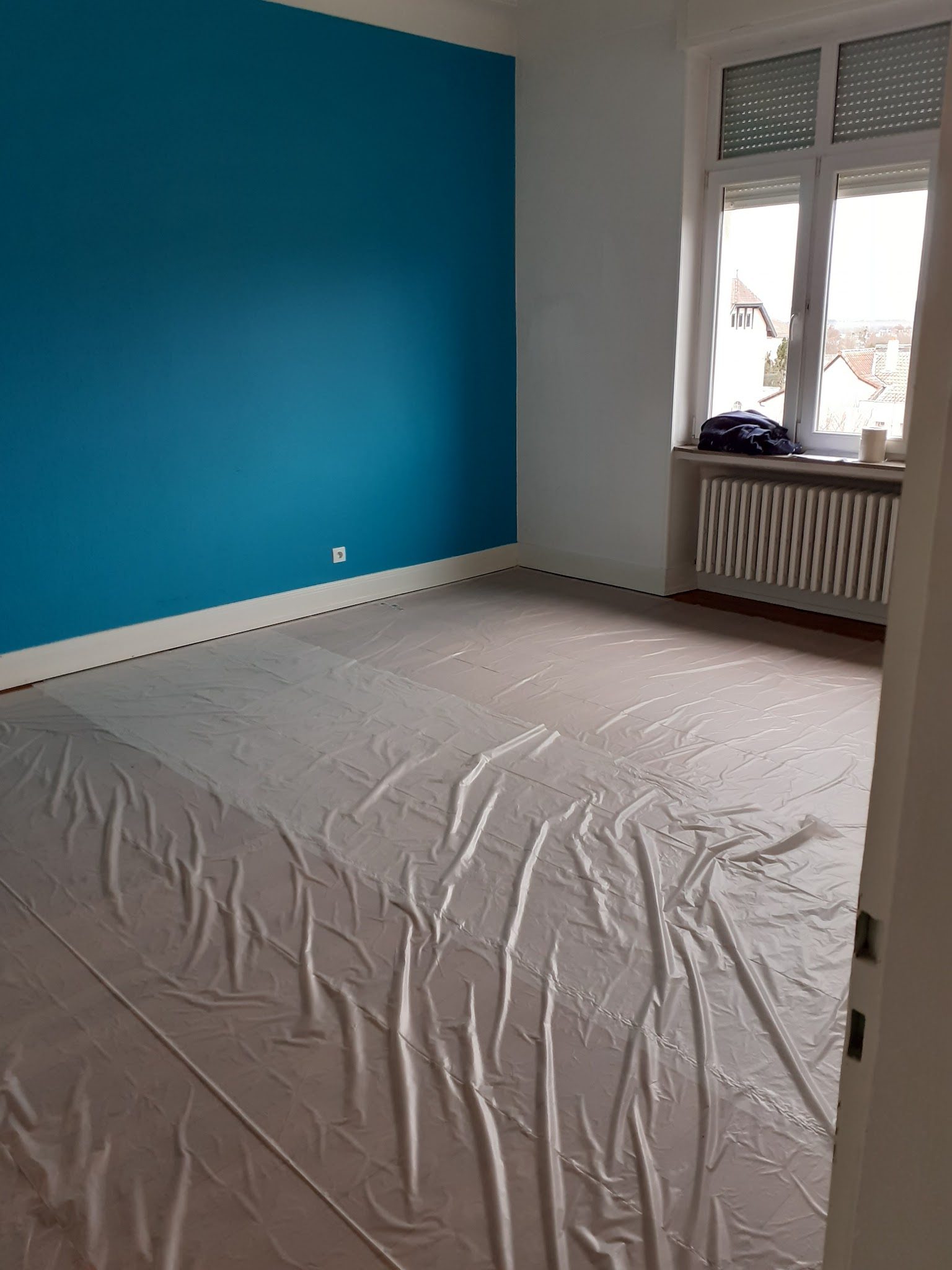 Chambre au mur bleu canard, sol bâché pendant les travaux