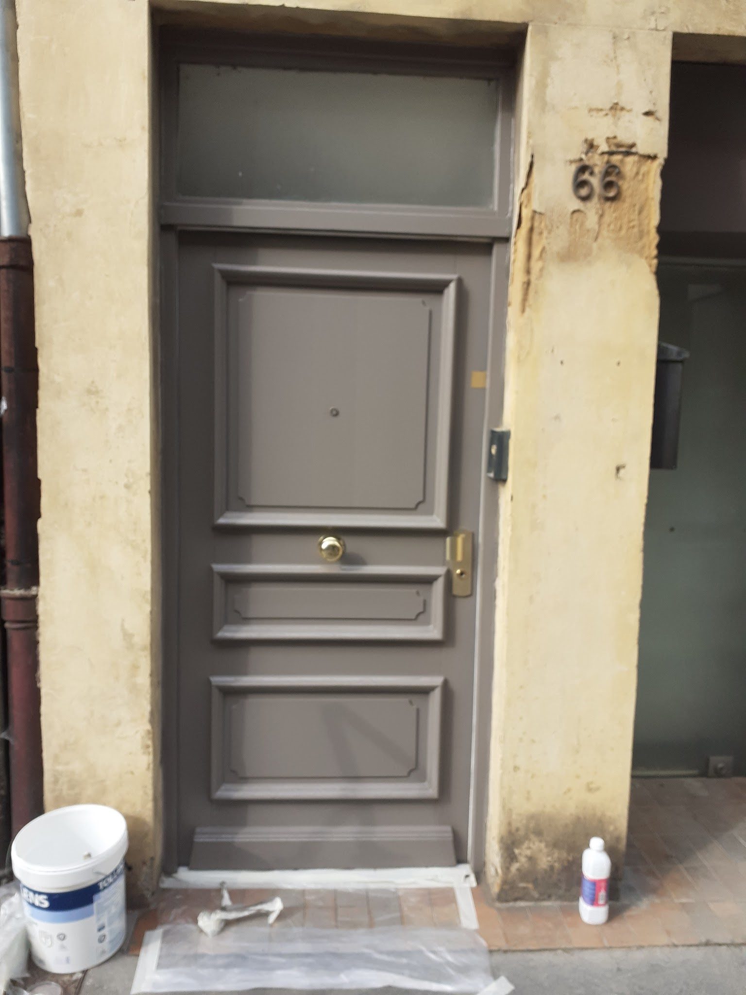 Porte d'entrée repeinte en gris dans un encadrement de pierre